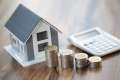 Foto: Modellhaus, Münzstapel und Taschenrechner