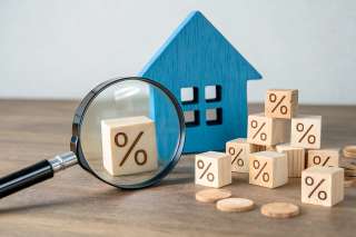 Foto: Lupe, Holzhaus und Würfel mit Prozentzeichen